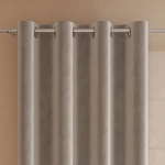 Zasłona gotowa welwetowa 140x260 cm w kolorze szaro-beżowym, na przelotkach. Produkt wiszący, ukazujący miękką tkaninę o gładkiej teksturze. Zdjęcie z boku, z widocznymi przelotkami ułatwiającymi montaż. Tło w odcieniu kremowym, minimalistyczne.