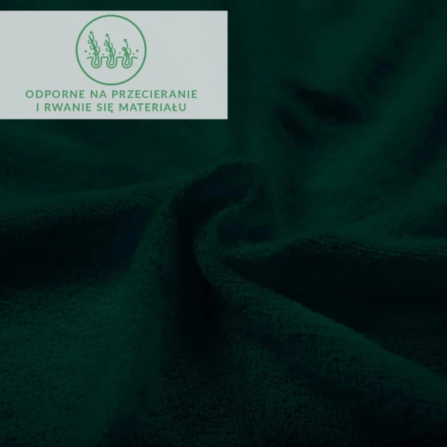 Prześcieradło frotte z gumką w kolorze zieleni butelkowej o gładkiej fakturze. Ułożone w złożony sposób, ukazujące miękkość materiału. Widoczne są oznaczenia dotyczące odporności na przecieranie i rwanie. Tło ciemne, co podkreśla głęboki kolor.
