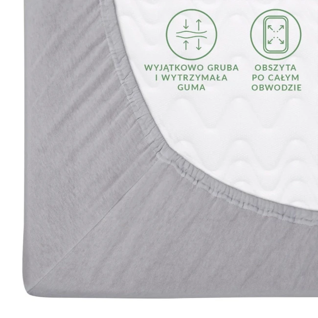Prześcieradło jersey z gumką 120x200 w kolorze popielatym. Zbliżenie na krawędź z mocną, elastyczną gumą. Widoczne informacje o właściwościach materiału: wyjątkowo gruba i wytrzymała guma, obszyta po całym obwodzie. Tło białe.