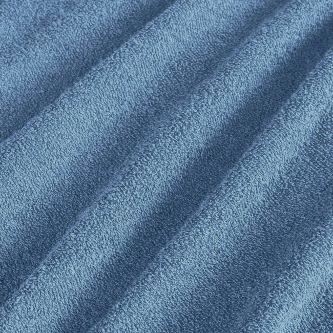 Pościel frotte 200x220 w kolorze niebieskim, wykonana z miękkiego materiału o wyraźnej teksturze. Złożona, zdjęcie wykonane w zbliżeniu, ukazujące szczegóły faktury tkaniny. Tło jednolite, co podkreśla kolor i strukturę materiału.