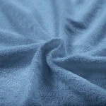 Pościel frotte w kolorze błękitnym o wymiarach 200x220, ułożona na płasko, z widoczną miękką i teksturowaną powierzchnią. Materiał jest przyjemny w dotyku, a subtelny kolor dodaje elegancji. Idealna do wnętrz sypialnianych.