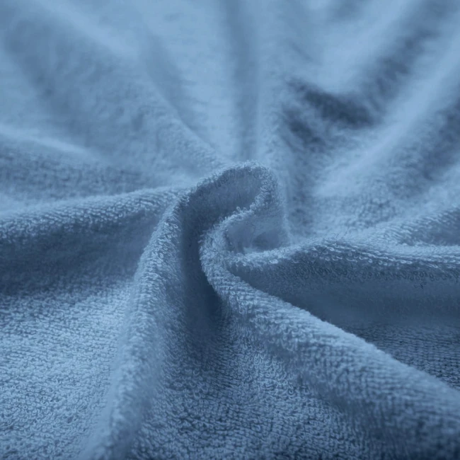 Pościel frotte w kolorze błękitnym o wymiarach 200x220, ułożona na płasko, z widoczną miękką i teksturowaną powierzchnią. Materiał jest przyjemny w dotyku, a subtelny kolor dodaje elegancji. Idealna do wnętrz sypialnianych.