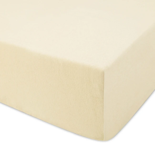 Prześcieradło jersey z gumką w kolorze kremowym, rozmiar 120x200, leżące z boku. Wykonane z miękkiego materiału, o delikatnej fakturze, dobrze dopasowujące się do materaca. Brak widocznych napisów lub logo.