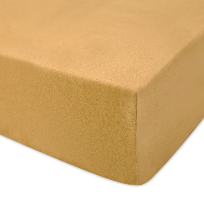 Prześcieradło jersey z gumką w kolorze musztardowym, o wymiarach 120x200 cm. Produkt leży płasko, z widoczną teksturą materiału, prezentującym gładką, matową powierzchnię. Brzeg prześcieradła jest starannie wykończony.