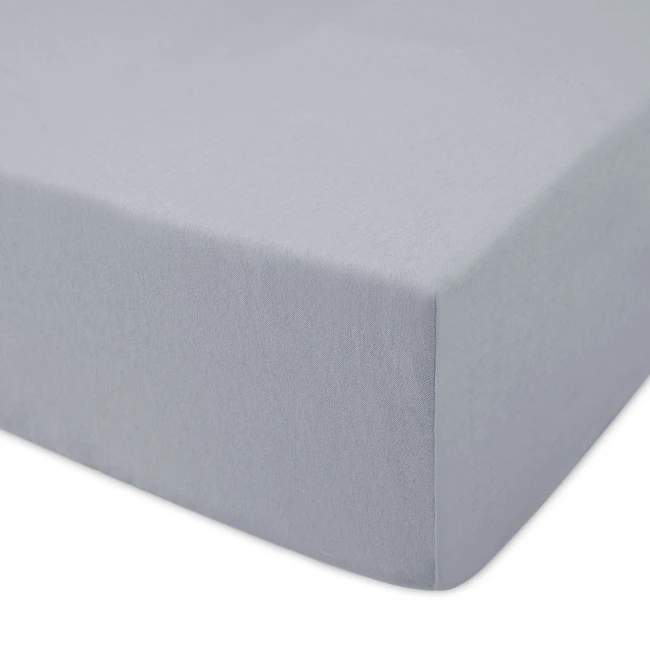 Prześcieradło jersey z gumką w kolorze popielatym, rozmiar 120x200 cm, leżące na płaskiej powierzchni. Materiał o gładkiej fakturze, z widocznym detalem gumki na krawędzi, która zapewnia stabilność. Tło białe, neutralne.