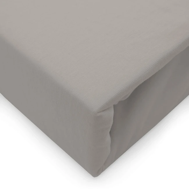 Prześcieradło jersey z elastanem w kolorze popielatym, rozmiar 140x200, leżące, ukazane z boku. Wykonane z elastycznego materiału, gładkie w dotyku. Widoczna gumka, która zapewnia dopasowanie. Proste tło podkreśla produkt.