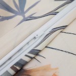 Poszewka satynowa 40x40 z kremowym tłem, ozdobiona wzorem polnych czerwonych kwiatów. W szczególności widoczny zamek błyskawiczny w białym kolorze. Ujęcie w zbliżeniu na detal materiału i zamka. Idealna do stylizacji wnętrz.