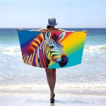Ręcznik plażowy 100x180 z mikrofibry, kolorowa zebra na tle tęczowych pasów. Ułożony w poziomie, trzymany przez osobę w kapeluszu, stojącą nad brzegiem morza. Szybkoschnący materiał, duży rozmiar idealny na plażę.