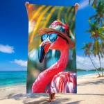 Ręcznik plażowy 100x180 cm z mikrofibry w różowy wzór flaminga w okularach i kapeluszu, prezentowany w pozycji pionowej. Tło plażowe z palmami i morzem, szybkoschnący materiał idealny na letnie dni.