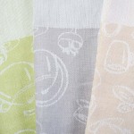 Ścierka kuchenna bawełniana 50x70 cm w kolorze zielonym z subtelnymi wzorami. Ułożona na płasko, ukazuje fakturę materiału. Wzory przedstawiają postacie oraz klasyczne symbole kuchenne. Tło neutralne, podkreślające detale tekstyliów.