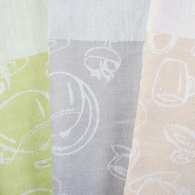 Ścierka kuchenna bawełniana 50x70 cm w kolorze zielonym z subtelnymi wzorami. Ułożona na płasko, ukazuje fakturę materiału. Wzory przedstawiają postacie oraz klasyczne symbole kuchenne. Tło neutralne, podkreślające detale tekstyliów.