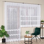 Firana gotowa WIKTORIA, żakardowa, biała, o wymiarach 200x250 cm, zawieszona na karniszu. Wzór z cienkimi liniami na delikatnej tkaninie. Ujęcie frontalne, firana rozłożona, w aranżacji wnętrza z zielonymi roślinami, stolikiem oraz krzesłem w tle.