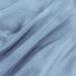 Pościel satyna bawełniana 180x200 w kolorze błękitnym, rozłożona na gładkiej powierzchni. Widoczna tekstura materiału, delikatne fale tkaniny podkreślają jej miękkość. Brak widocznych napisów lub logo.