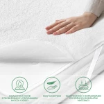 Ochraniacz na materac 90x180 cm w kolorze białym, z miękką, teksturowaną powierzchnią. Ujęcie z boku, pokazujące dłoń dotykającą materiału. Elastyczny, dopasowujący się do różnych typów materacy, idealny dla osób z problemami zdrowotnymi.