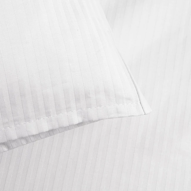 Pościel hotelowa bawełniana 160x200 w pasy 4-mm biała na zakładkę 30 cm, nawiązująca do eleganckiego wystroju. Widok z bliska, pokazujący detale faktury i wzoru, z poduszką w pasy leżącą na płaskiej powierzchni.