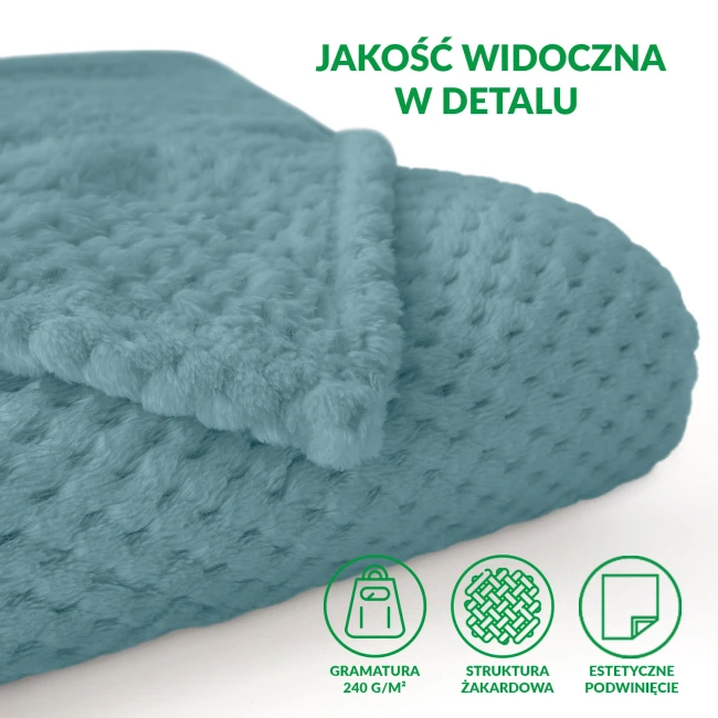 Koc żakardowy 150x200 w jasnym turkusowym kolorze, rozłożony na jednolitym tle. Wyróżniająca się teksturowana powierzchnia z drobnym wzorem. Widoczna krawędź z podwinięciem, co podkreśla jego miękkość i komfort.