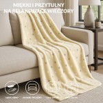 Puszysty koc dekoracyjny 150x200 cm w kolorze żółtym z limonkowymi kropkami, wykonany z miękkiego materiału. Rozłożony na beżowej kanapie, idealny do użytku w domu. Koc jest lekki, ciepły i przeznaczony na sofę lub łóżko.