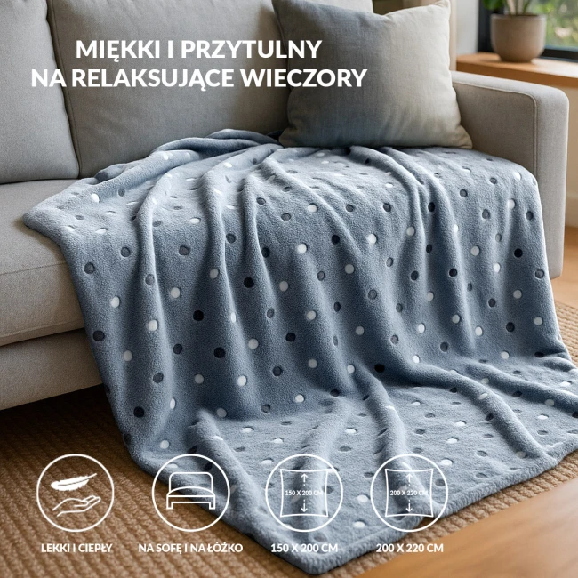 Puszysty koc dekoracyjny w kolorze ciemnego niebieskiego (navy) o wymiarach 200x220 cm, z delikatnymi, jasnymi kropkami. Leży na sofie, prezentując miękką fakturę, idealny na chłodne wieczory.