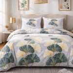 Pościel flanelowa 220x200 cm w kolorze szarym z wzorem liści miłorzębu. Złożona na łóżku, poduszki w tym samym wzorze umieszczone z tyłu. Ułożenie na gładkim tle, obok lampka nocna. Wzór dekoracyjny z liśćmi w odcieniach zieleni i beżu.