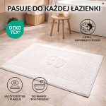 Dywanik łazienkowy 50x70 cm w kolorze białym, o teksturowanej powierzchni, leżący na podłodze w nowoczesnej łazience.