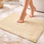 Dywanik łazienkowy 50x70 w kolorze kremowym, o gładkiej fakturze, leżący na podłodze. Otoczenie to nowoczesna łazienka