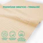 Dywanik łazienkowy o wymiarach 50x70 cm w kolorze kremowym. Ułożony na płasko, z fakturą pokrytą małymi wypustkami. Materiał tekstylny, bez widocznych napisów czy logo, na jednolitym tle. Design minimalistyczny, idealny do użytku w łazience.