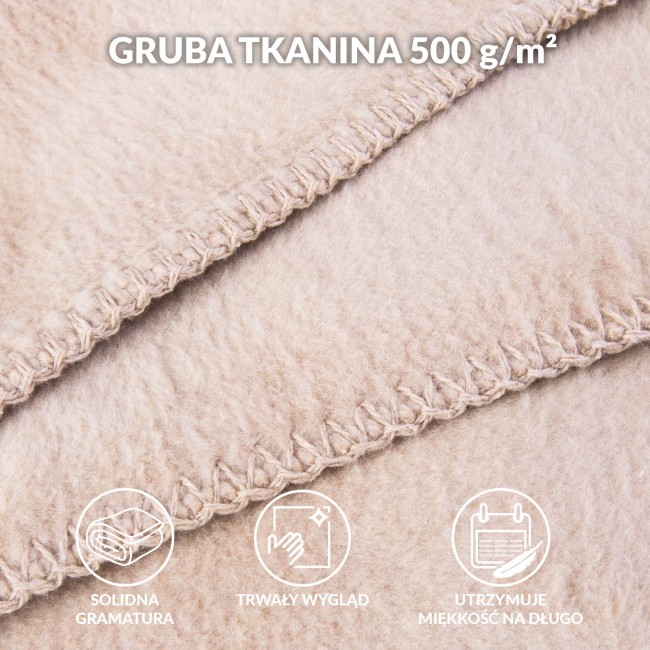 Koc bawełniany w jasnym beżu o wymiarach 150x200 cm, leżący na płaskiej powierzchni. Widoczna tekstura materiału oraz estetyczne frędzle przy brzegach. Zbliżenie na strefę ściegów, podkreślające staranne wykończenie.