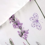 Pościel bawełniana 220x200 Lavenda w kolorze białym z motywem fioletowej lawendy i motyla. Widoczna tekstura tkaniny, delikatne detale kwiatów. Pozycja leżąca, zbliżenie na wzór.