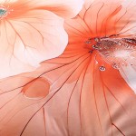 Pościel satyna bawełniana 160x200 Camellia w kremowym kolorze z pomarańczowymi kwiatami. Wzór przedstawia szczegółowe, delikatne kwiaty z widocznymi żyłkami i kroplami wody, na gładkiej, błyszczącej tkaninie.