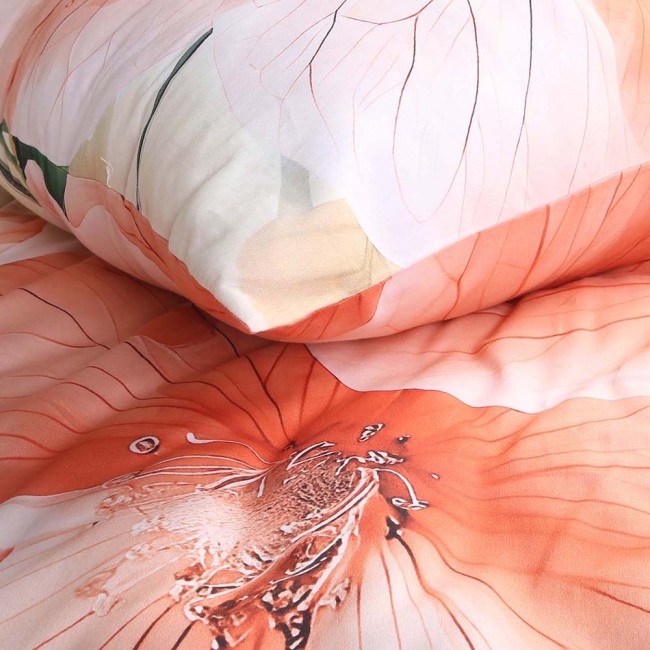 Pościel satynowa w kolorze kremowym z pomarańczowymi kwiatami, zestaw 180x200 cm. Wzór kwiatowy na narzucie i poduszce, z wyraźnymi detalami. Materiał gładki, leżący na łóżku, z poduszką w tle.