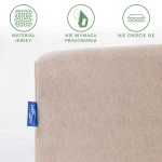 Prześcieradło jersey z gumką 80x160 w kolorze beżowym, widoczne na zdjęciu, leży na płaskiej powierzchni. Zbliżenie na materiał ukazuje jego gładką i elastyczną teksturę.